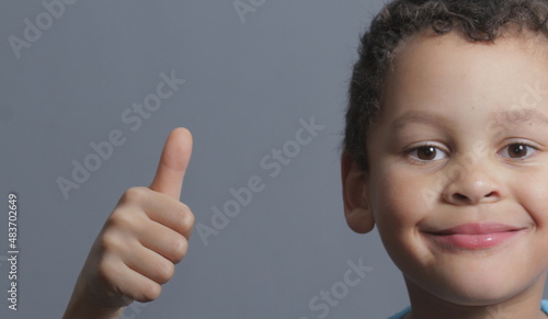 boy with thumbs up gesture on grey background stock photo
