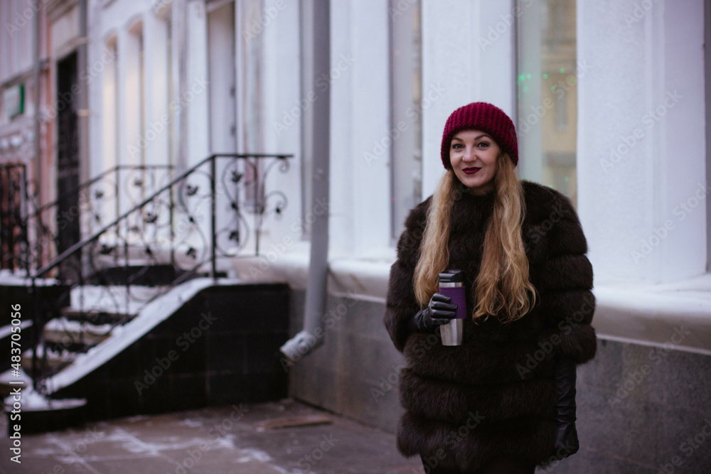 Fototapeta premium portrait of a white girl in winter in a fur coat who walks through the streets of the city