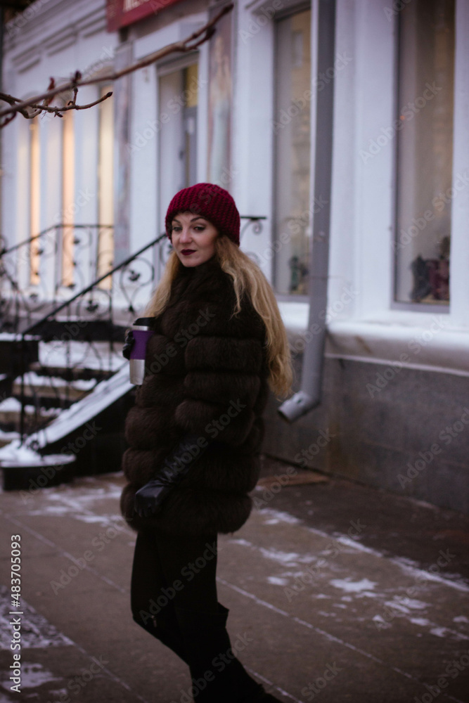 portrait of a white girl in winter in a fur coat who walks through the streets of the city