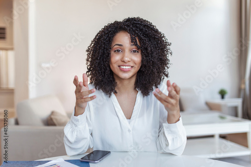 African-american elegant female entrepreneur discussing while having a conference call Portrait of confident ethnicity female employee looking at camera talking on video call in the home office. photo