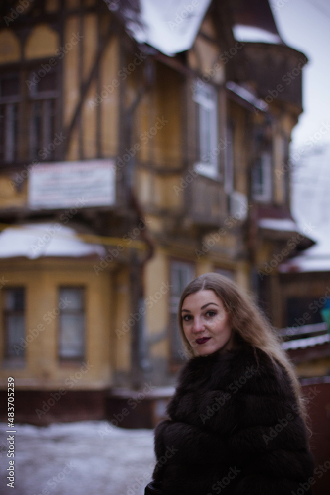 Naklejka premium portrait of a white girl in winter in a fur coat who walks through the streets of the city