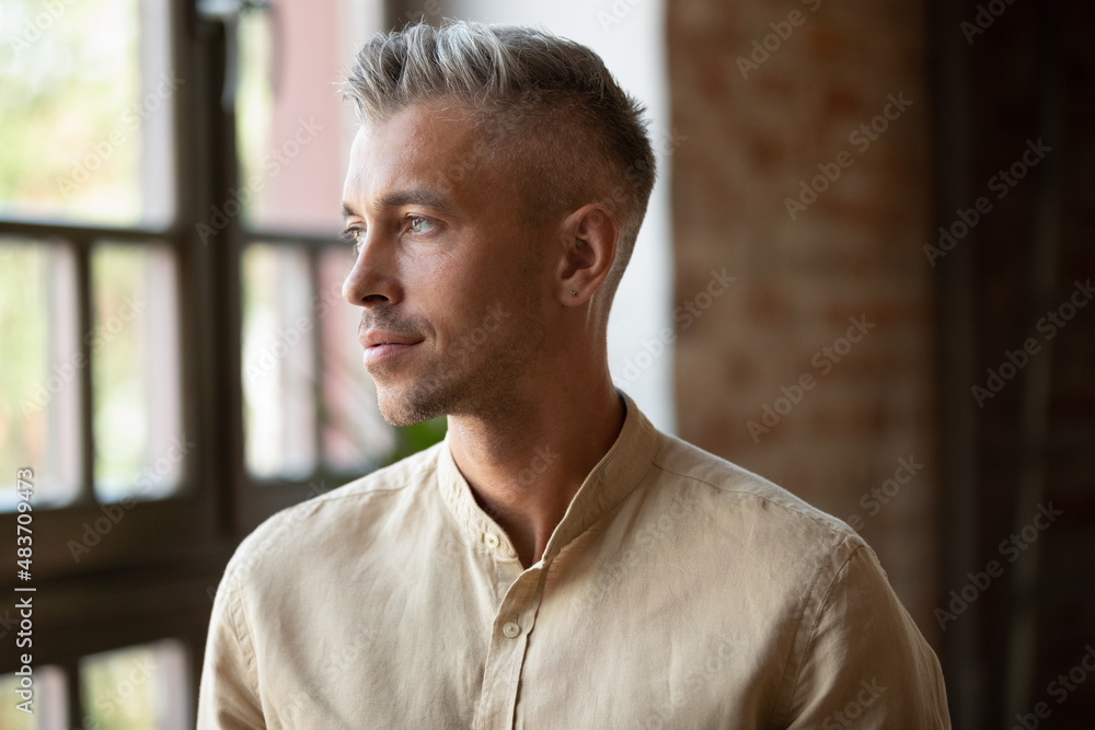 Serious thoughtful handsome millennial grey haired business man, entrepreneur looking at window away in deep thoughts, thinking of business project vision, career, company future. Head shot portrait Serious thoughtful handsome millennial grey haired business man, entrepreneur looking at window away in deep thoughts, thinking of business project vision, career, company future. Head shot portrait