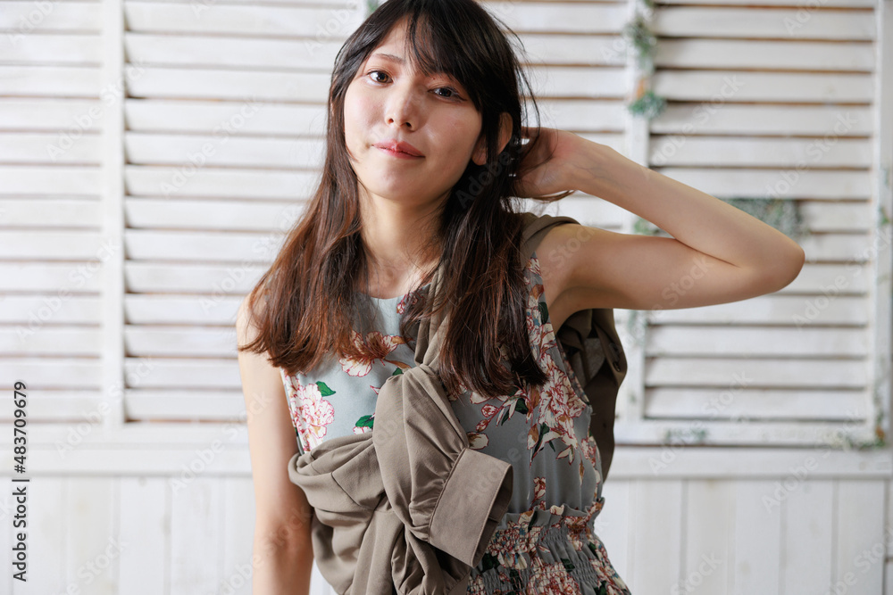 おしゃれな背景の前でポーズをする袖なしワンピースの日本人女性 おしゃれな背景の前でポーズをする袖なしワンピースの日本人女性
