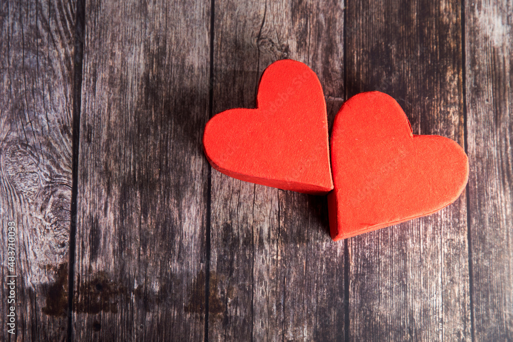 Two red paper hearts are next to each other on a wooden brown table. The day of Valentine. Copy space Two red paper hearts are next to each other on a wooden brown table. The day of Valentine. Copy space