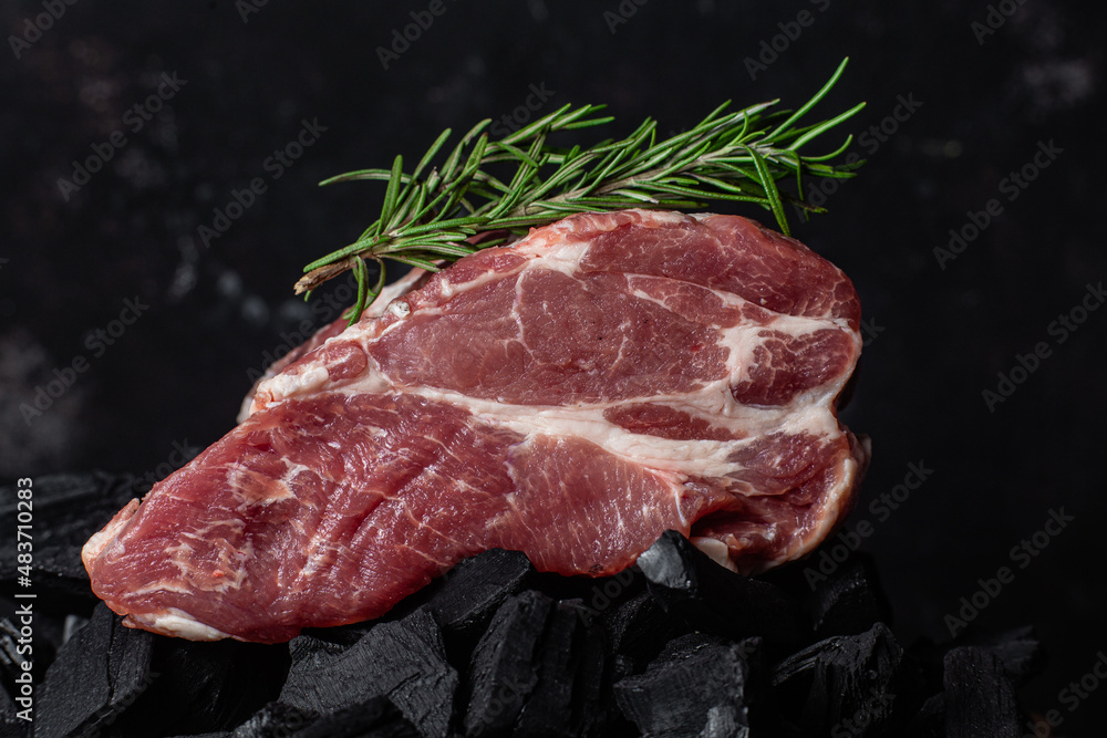 A piece of raw pork on the coals close-up