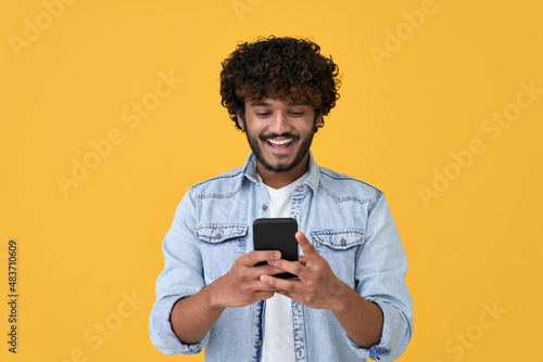 Foto Happy indian young man using cell phone isolated on yellow background