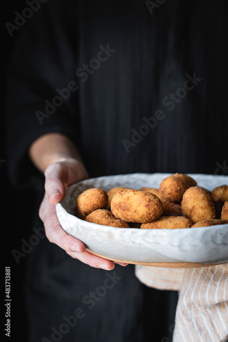 Potato croquettes being held by a woman in a black top, with copy space photo