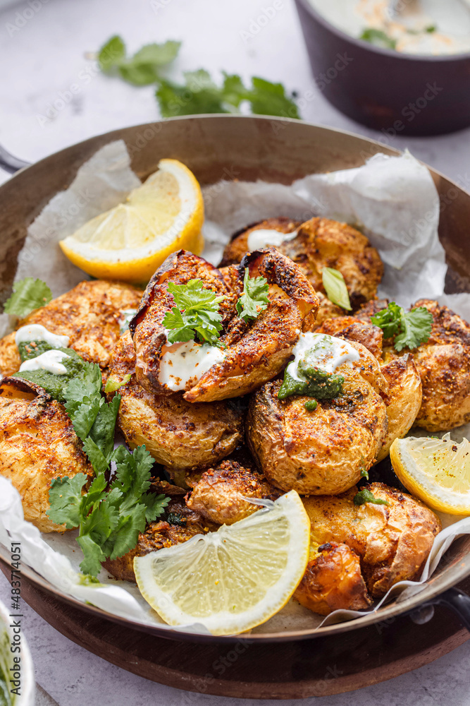 A serving platter with curried indian mashed potatoes, garnished with coriander leaves and lemon