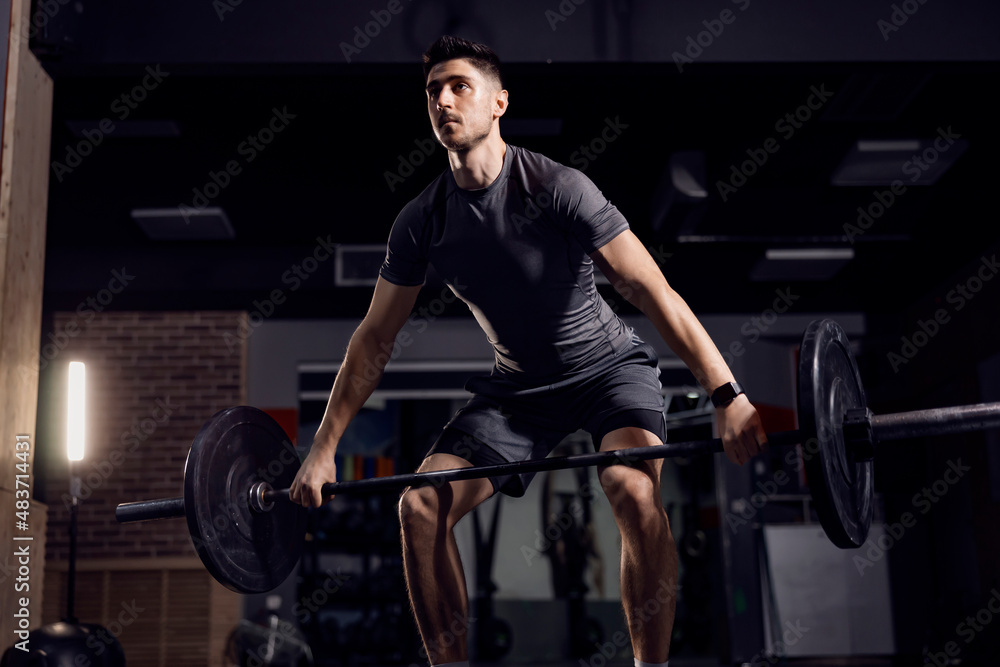 A strong man doing lifting heavy weights at the gym and exercising his biceps. A strong man doing lifting heavy weights at the gym and exercising his biceps.