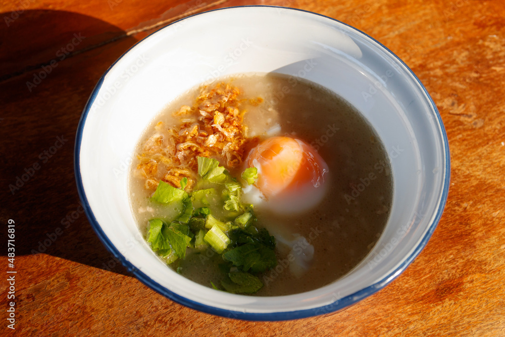 Rice congee with soft-boiled egg on morning sunlight.