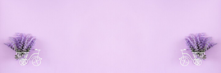 Small white bicycle with lavender bouquet in basket on pastel purple background. Spring floral banner background