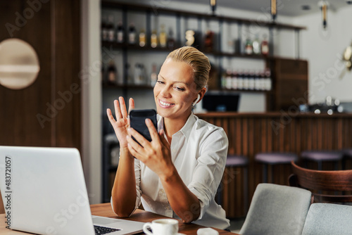 A businesswoman sitting in cafe and using smart phone for a business call.