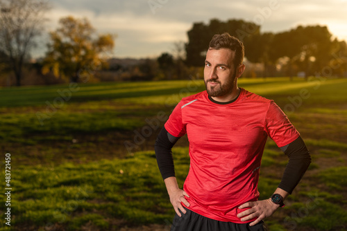 Confident sportsman standing with hands on waist in park