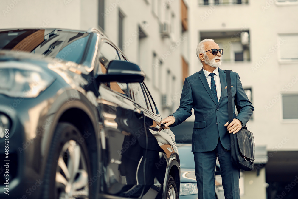 An old businessman opening his car. 