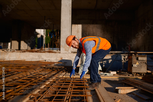 Construction worker taking metal grid reinforcing armature
