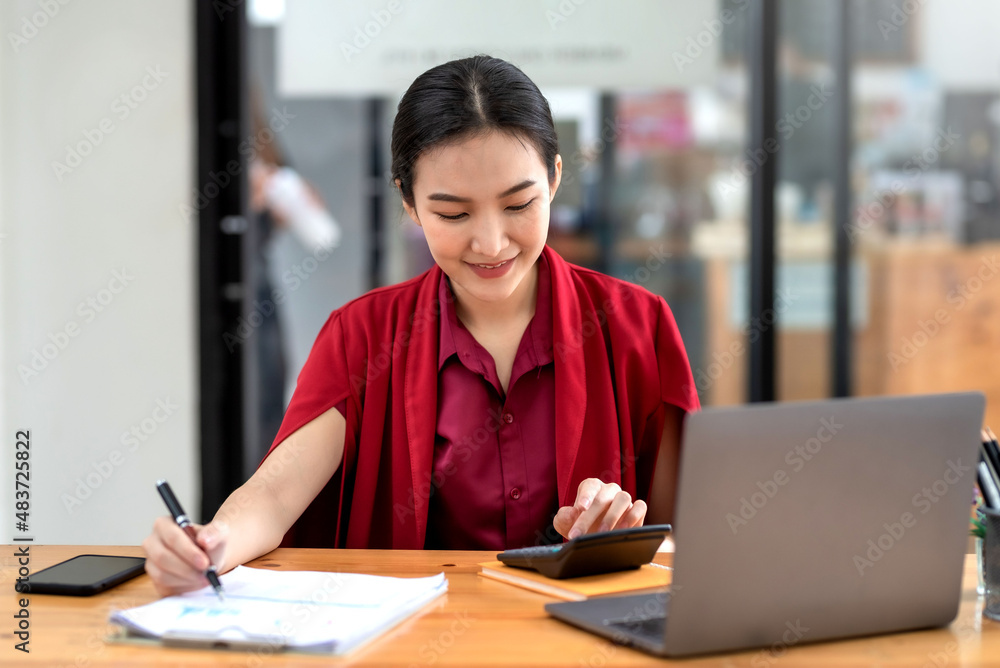Confident young Asian businesswoman sitting working at her workplace at modern office. Confident young Asian businesswoman sitting working at her workplace at modern office.