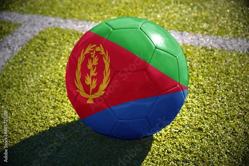football ball with the national flag of eritrea lies on the green field