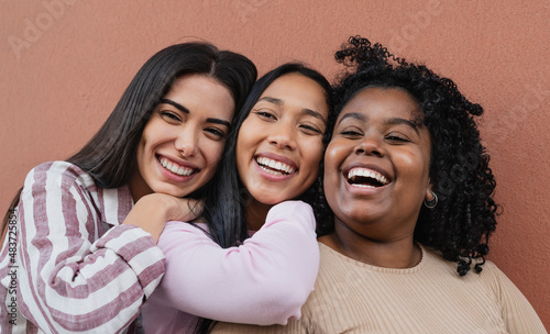 Happy multiracial friends embracing and smiling in front of camera