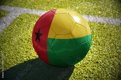 football ball with the national flag of guinea bissau lies on the green field