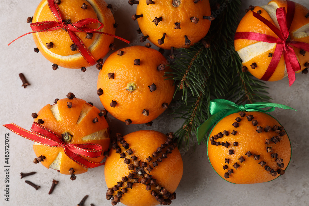 Pomander balls made of tangerines with cloves and fir branches on grey table, flat lay