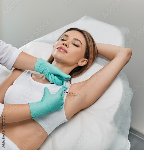 Woman receiving underarm hyperhidrosis treatment. Armpit injections to prevent excessive sweating with beautician at cosmetology photo