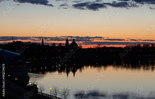 Sunset on Dnieper river. Beautiful Orange cloudy sky  city and church silhouettes reflecting in the river. Pleasant spring photo taken in Rechytsa  Belarus