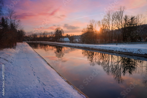 dreamy winter sunset at Isar river Schaftlarn, reflecting trees in the water, pink clouds