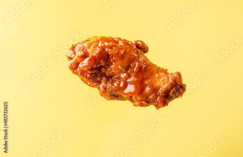 A piece of fried buffalo chicken wing on a bright background.
