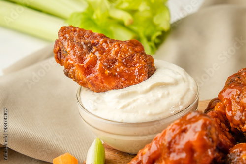 A piece of buffalo chicken wing in white blue cheese sauce, close-up.