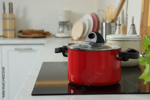 Red pot on electric stove in kitchen. Cooking utensil