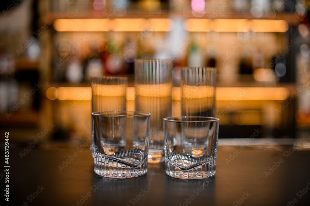 Set of empty clean glasses on dark bar counter.