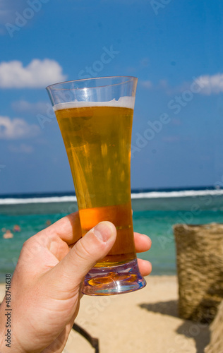 Hand with a glass of beer on the background of the sea