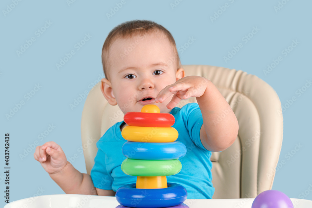 Joyful toddler 12-17 months old with his mouth open in surprise builds a pyramid tower of colored rings for the first time. Joyful toddler 12-17 months old with his mouth open in surprise builds a pyramid tower of colored rings for the first time.