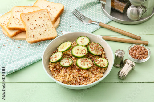 Bowl with tasty oatmeal  flax seeds and cucumber on table