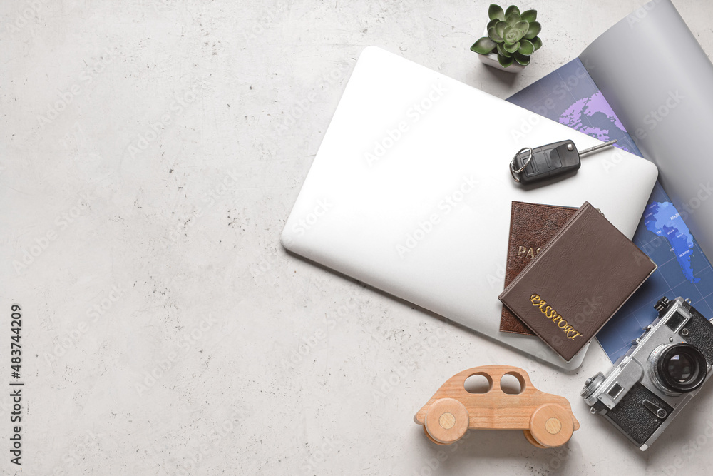 Fototapeta premium Laptop with toy car, photo camera, passports and map on light background