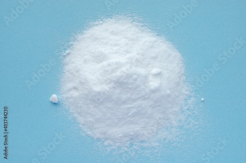 Pile of baking soda on a blue background, top view. Baking soda, sodium bicarbonate, on a blue background, top view. Baking soda powder, on a blue background, NaHCO3, top view.