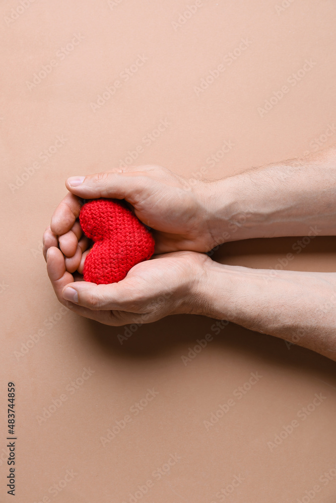 Obraz premium Male hands with knitted heart on color background. Donation concept