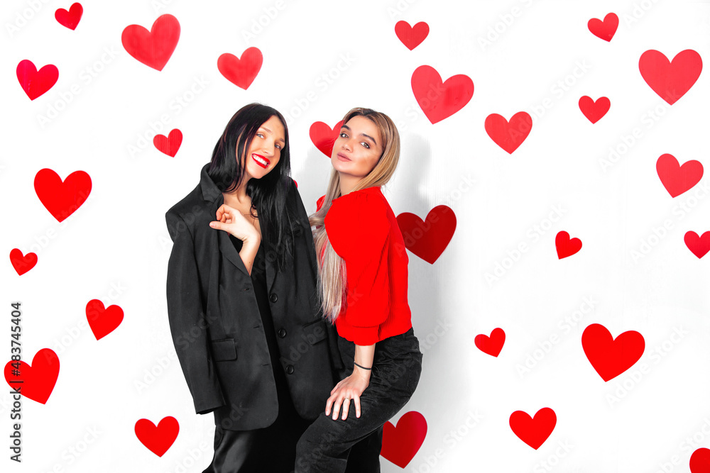 Two young adult women friends beautiful and happy together having fun with hearts on the background