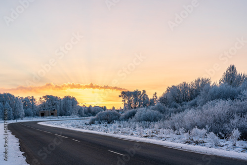 A smoke above town at sunrise. Winter road landscape with frost.