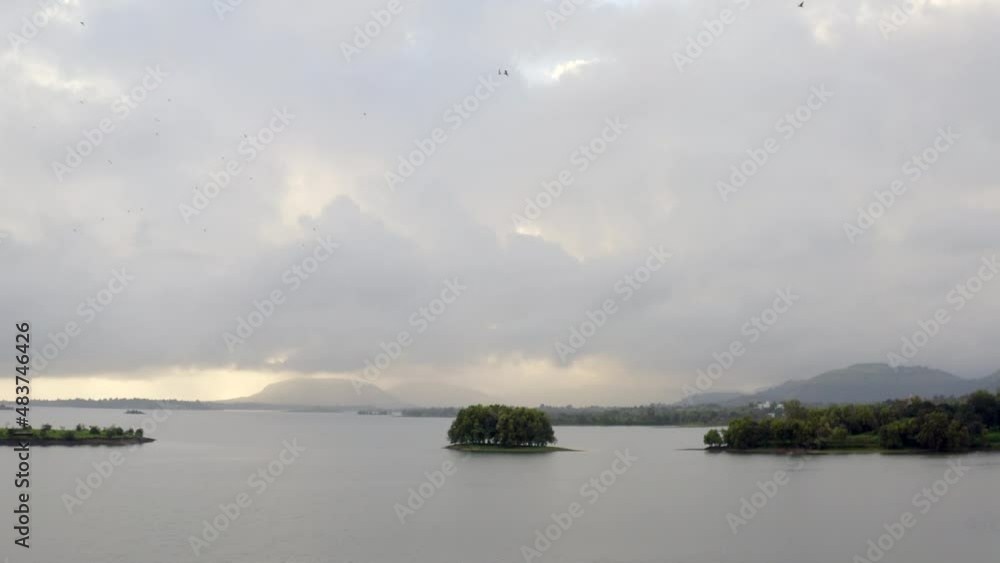 Vaitarna Lake With Flock Of Birds Flying During A Cloudy Day In Maharashtra, India - aerial drone shot Vaitarna Lake With Flock Of Birds Flying During A Cloudy Day In Maharashtra, India - aerial drone shot
