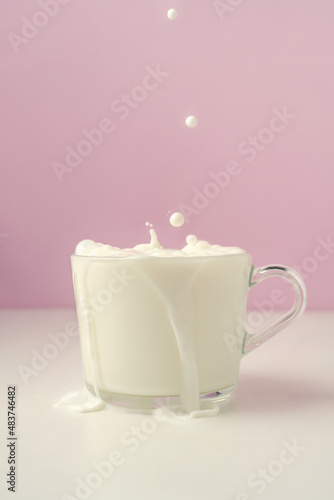 Milk is poured into a transparent cup on a purple background.