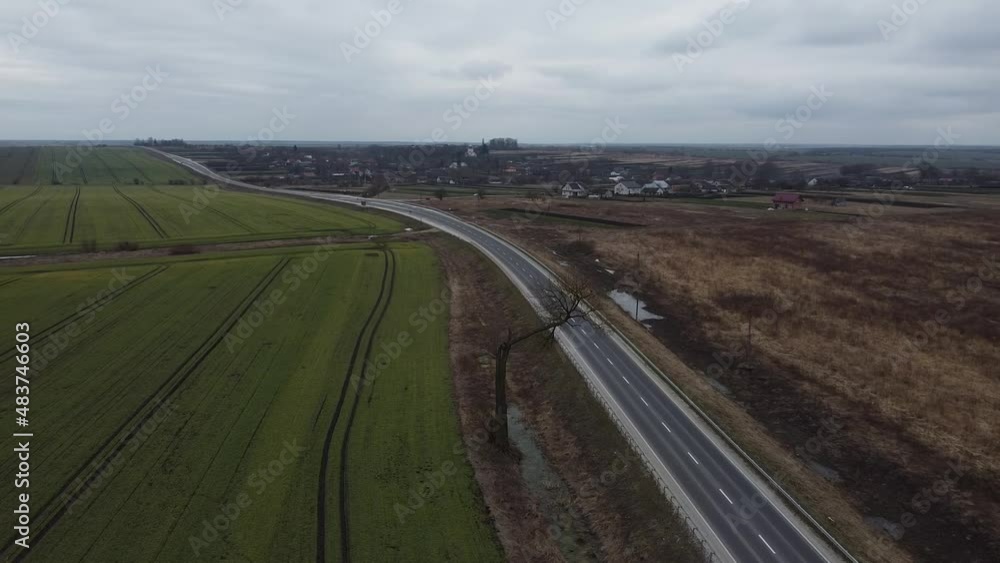 Aerial drone shot of curvy lonely road near Lviv Western Ukraine. Car driving fast on brand new road after construction surrounded by crop field on cloudy gloomy autumn day. Aerial drone shot of curvy lonely road near Lviv Western Ukraine. Car driving fast on brand new road after construction surrounded by crop field on cloudy gloomy autumn day.