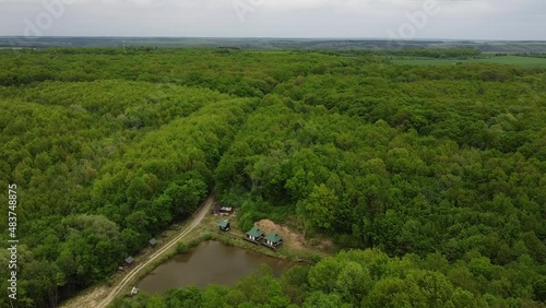 Aerial drone shot of beautiful natural outdoor landscape overlooking small triangular lake surrounded by forest in West Ukraine in Eastern Europe on cloudy summer day. Tourist attraction for leasure.