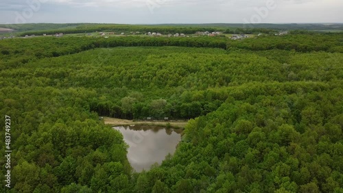 Aerial drone shot of beautiful natural outdoor landscape overlooking small triangular lake surrounded by forest in West Ukraine in Eastern Europe on cloudy summer day. Tourist attraction for leasure.