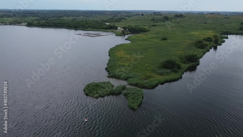 Aerial drone shot of beautiful natural outdoor landscape with blue lake and lonely boat near  Lviv West Ukraine in Eastern Europe on dark cloudy moody summer day. Tourist attraction for sailing.