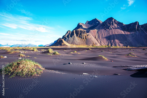 Obraz na płótnie Scenic landscape with most breathtaking mountains Vestrahorn on the Stokksnes peninsula and cozy lagoon with green grass on the sand dunes in Iceland. Exotic countries. Amazing places. w salonie