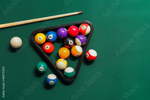 Different billiard balls with cue and rack on green table photo