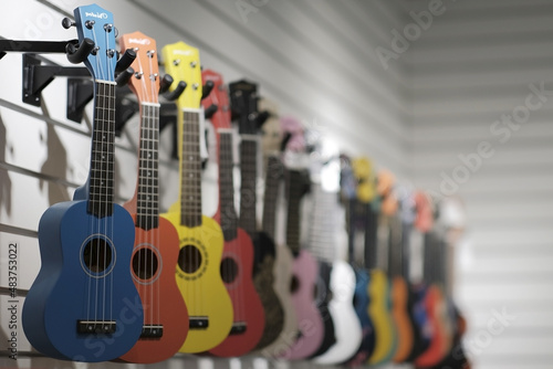 Multicolored acoustic guitars hang in a row in a music store on a white background
