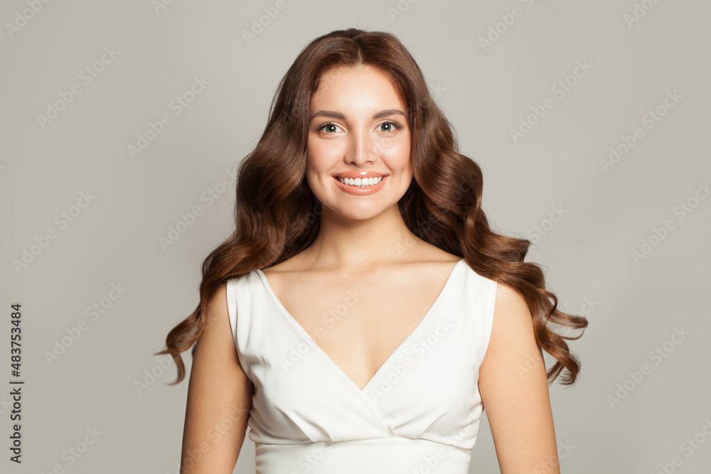 Nice woman with long curly beautiful hair smiling on gray background Nice woman with long curly beautiful hair smiling on gray background