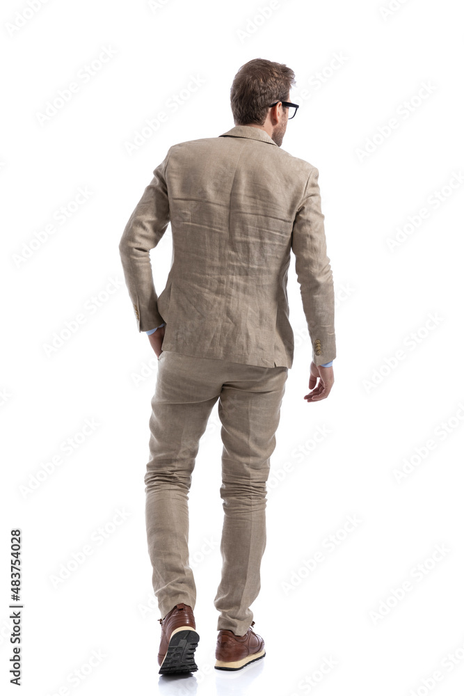 Naklejka premium businessman walking with a hand in pocket, looking to side